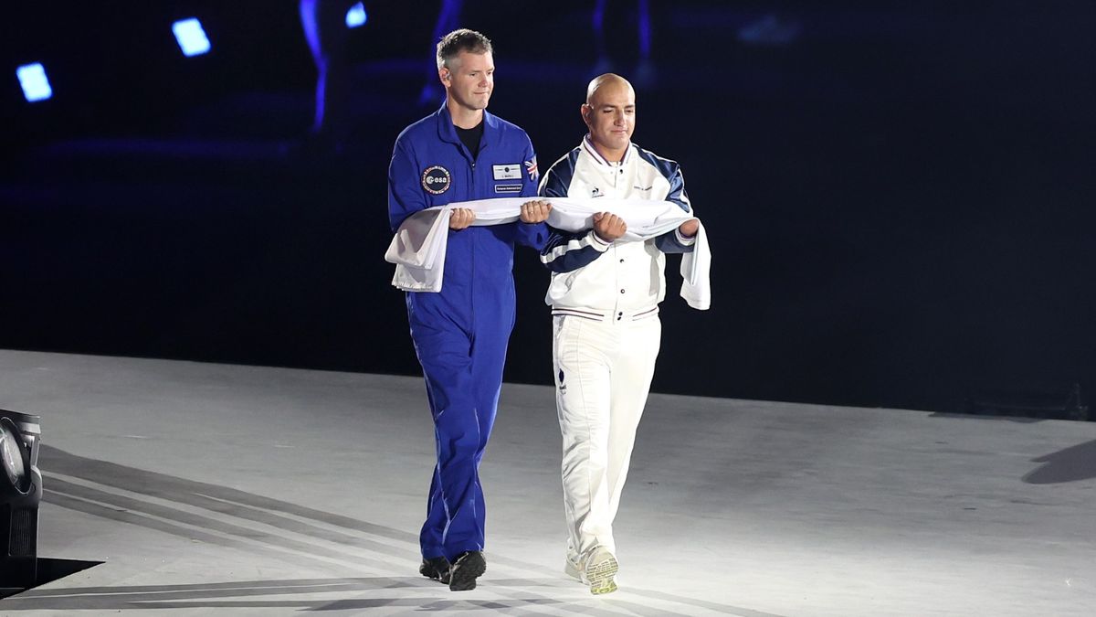 El astronauta John McFall lleva la bandera paralímpica en la ceremonia de apertura el 28 de agosto